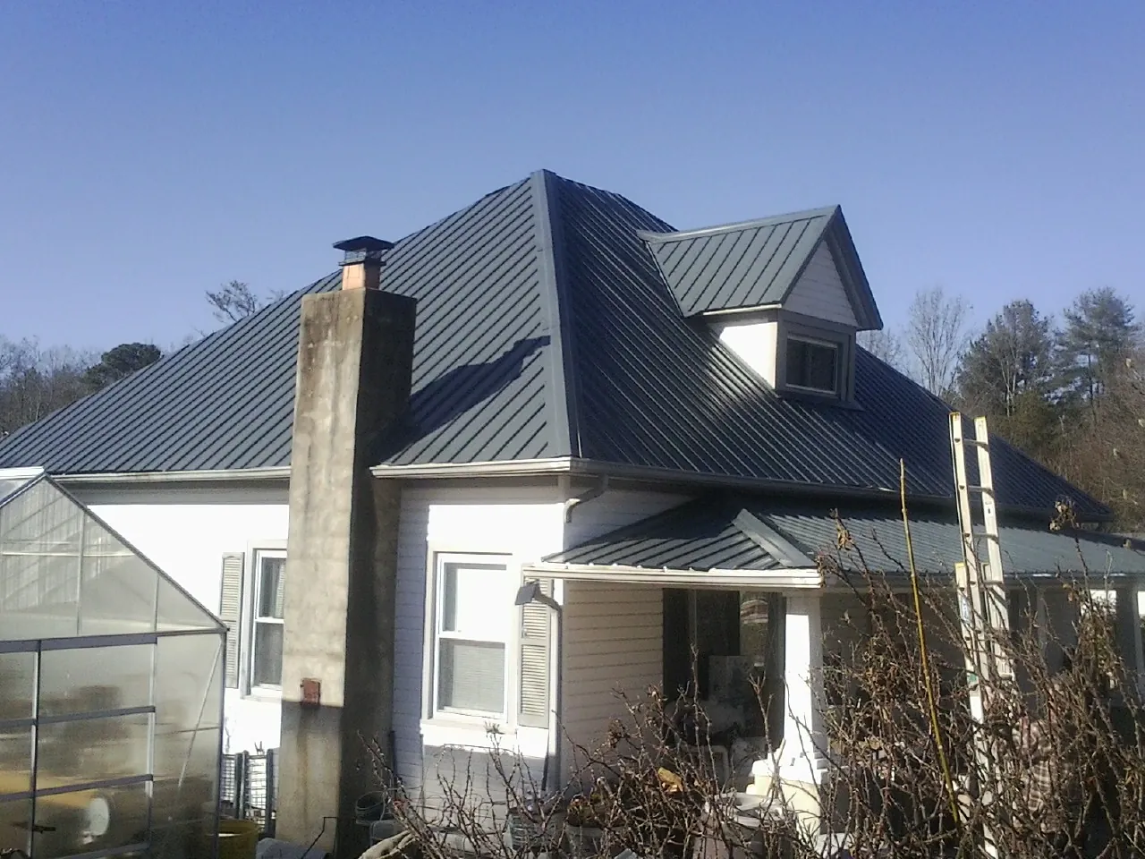 Dark blue standing seam metal roof on a white farmhouse with dormer — Slate & Tile Roof Repair by Roofing Brothers in Lanesborough