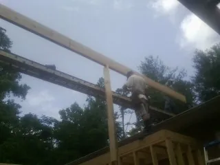 Carpenter setting a ridge beam over a new addition frame — Ice Dam Removal by Roofing Brothers in Lanesborough