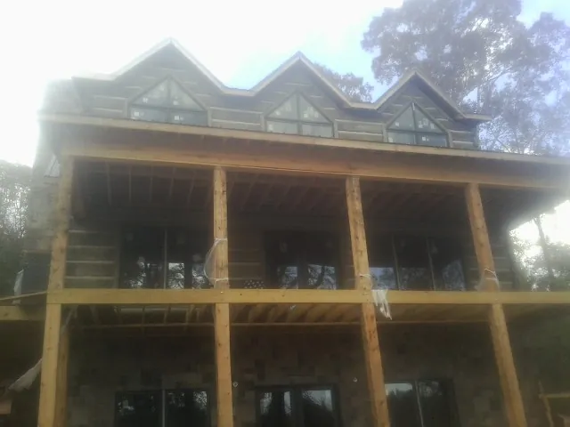 Dormers and porch framing on a large log home under construction — Roof Coating work by our crew in Lanesborough