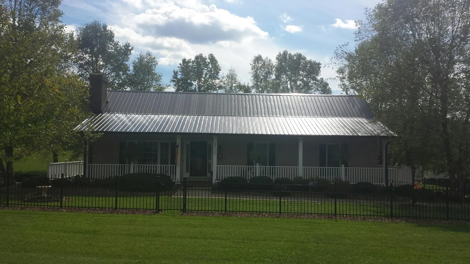 Gray metal roof on a brick ranch with a full width front porch — Gutter Guard Installation work by our crew in Lanesborough