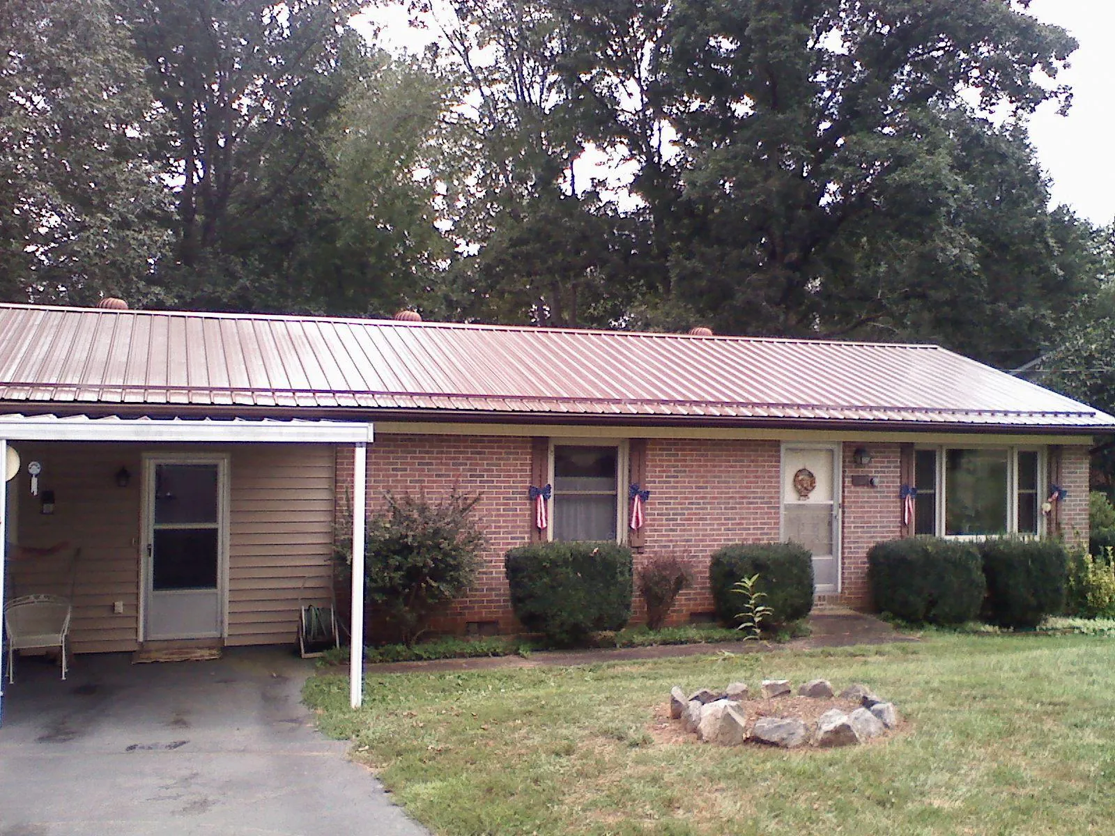 Bronze metal roof and carport on a brick ranch home — Roof Repair work by our crew in Lanesborough