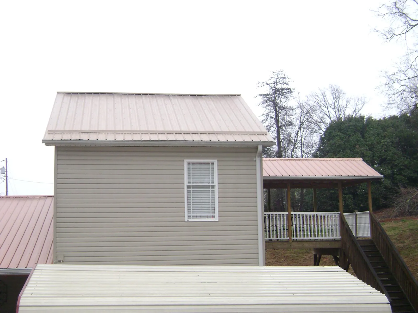 Tan metal roofs on a two story addition and attached porch, from a Roof Replacement job in Lanesborough