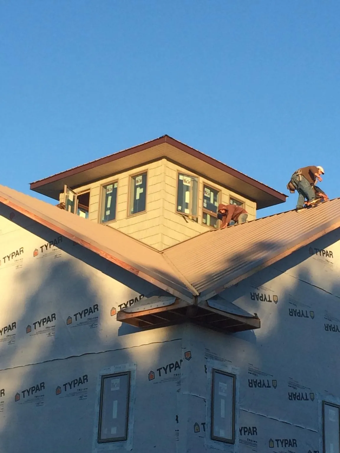 Roofers working around a rooftop cupola on a new metal roof at sunset — Roof Waterproofing in Lanesborough by Roofing Brothers